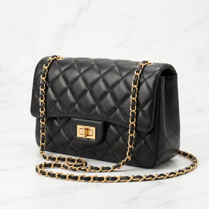 Black quilted handbag with gold chain strap on a white background