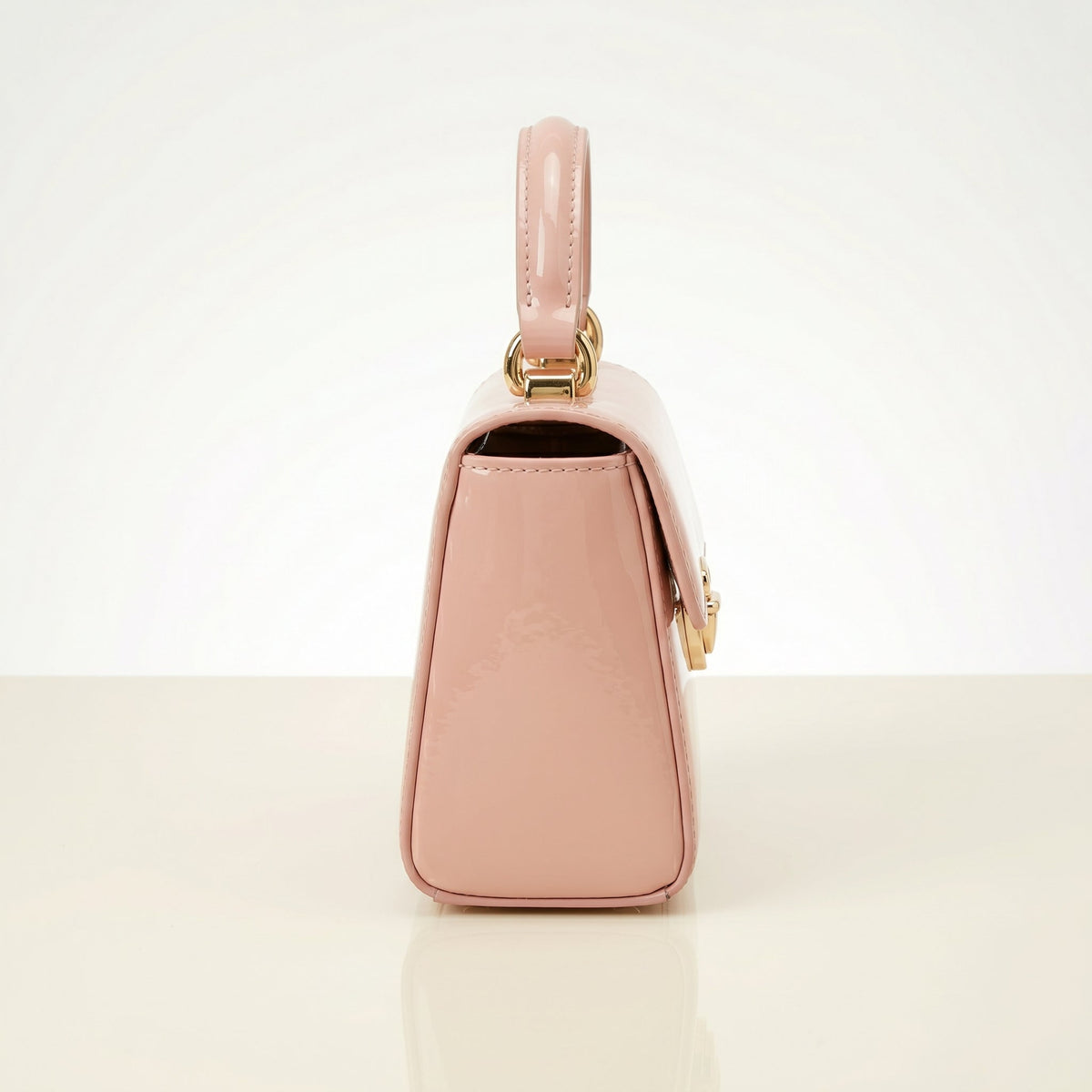 Pink handbag with gold accents on a light beige background
