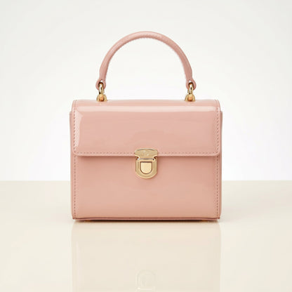 Pink handbag with gold accents on a light beige background
