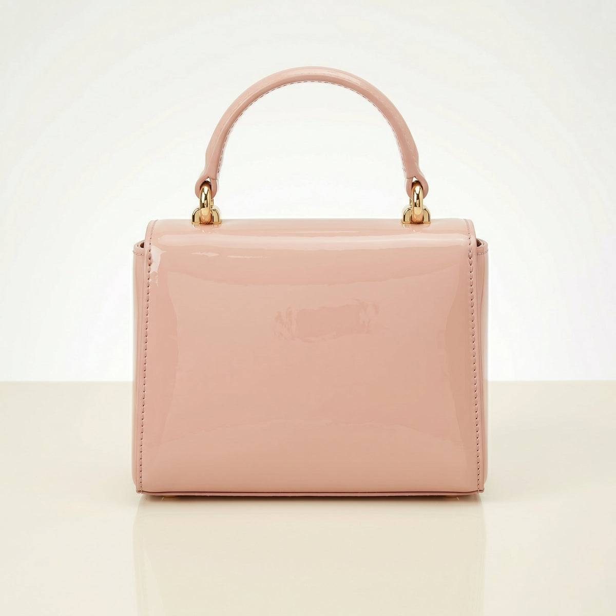Pink handbag with gold handle on a light beige background